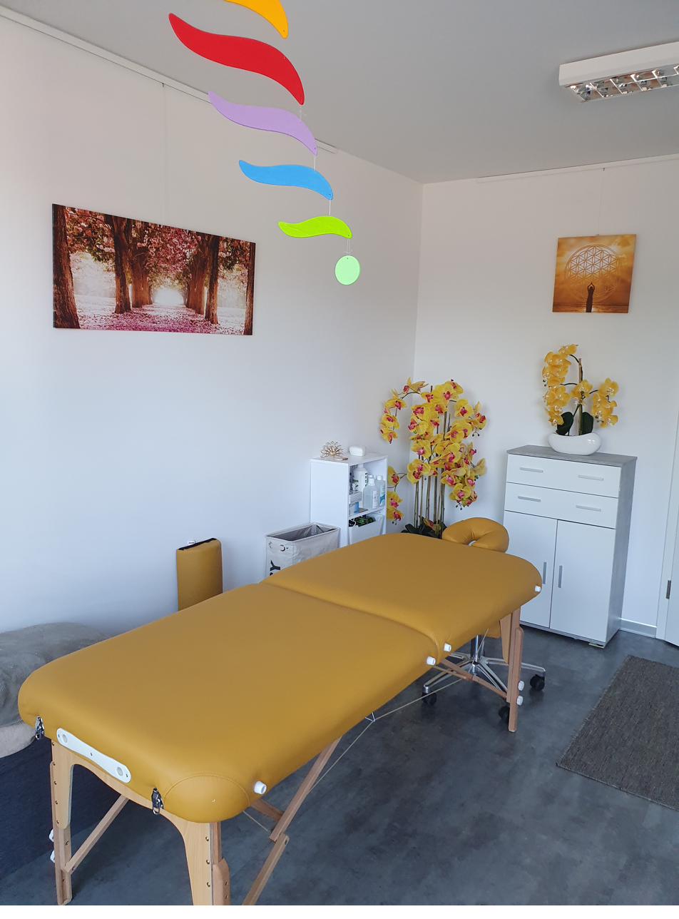 Heller Behandlungsraum mit Liege, Orchideen und einem Mobile
